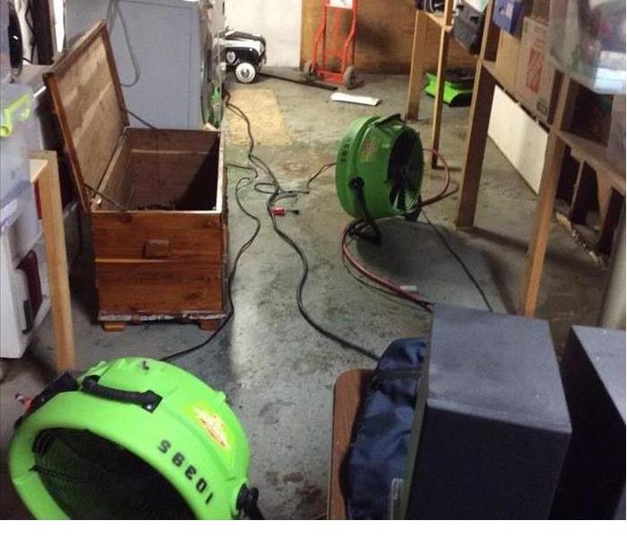 water damaged basement that has had water drained and a servpro machine 